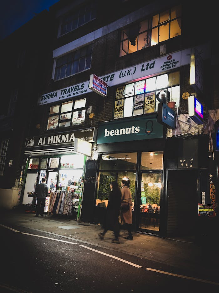 Street scene at night showcasing illuminated shops and pedestrians on a city street, creating a vibrant urban atmosphere.