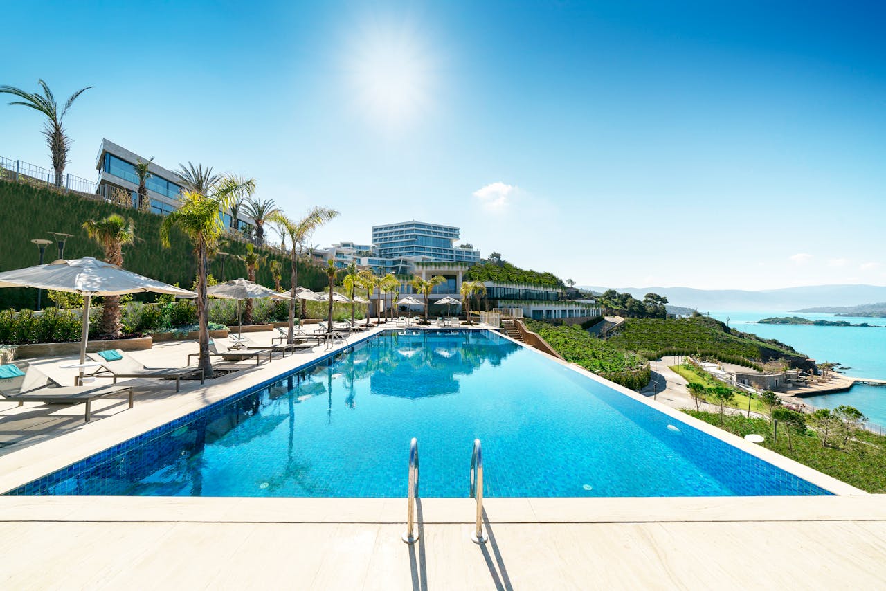team-06 A luxurious seaside resort in Bodrum, Turkey, featuring a stunning infinity pool under sunny skies.