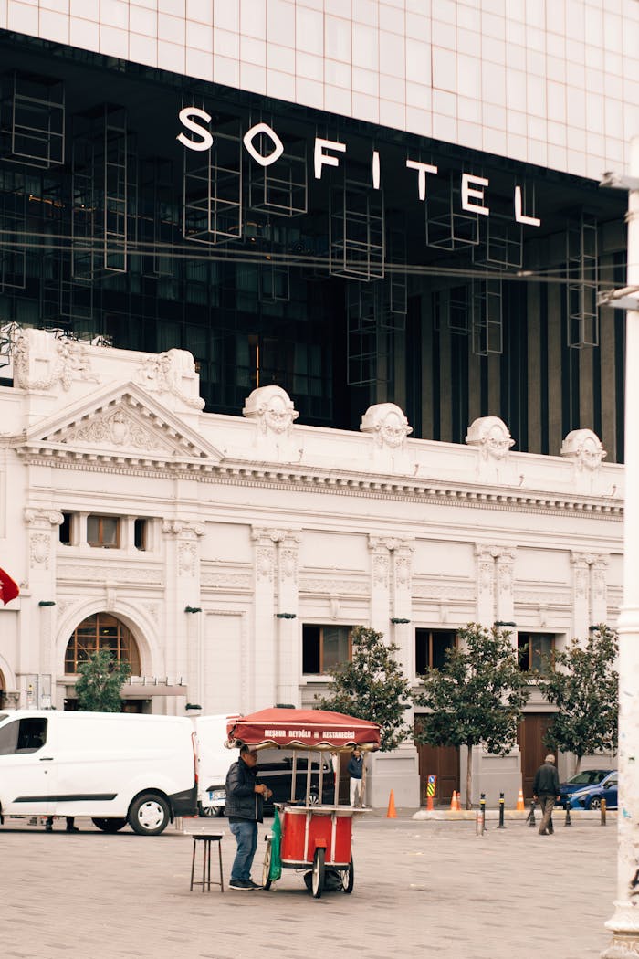 team-01 Street food cart with people near classic architecture of Sofitel Hotel.