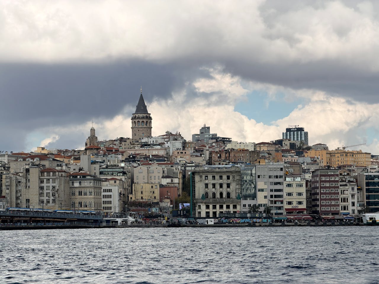 services-03 A picturesque scene of Istanbul's Galata Tower and skyline viewed from the Bosphorus on a cloudy day.
