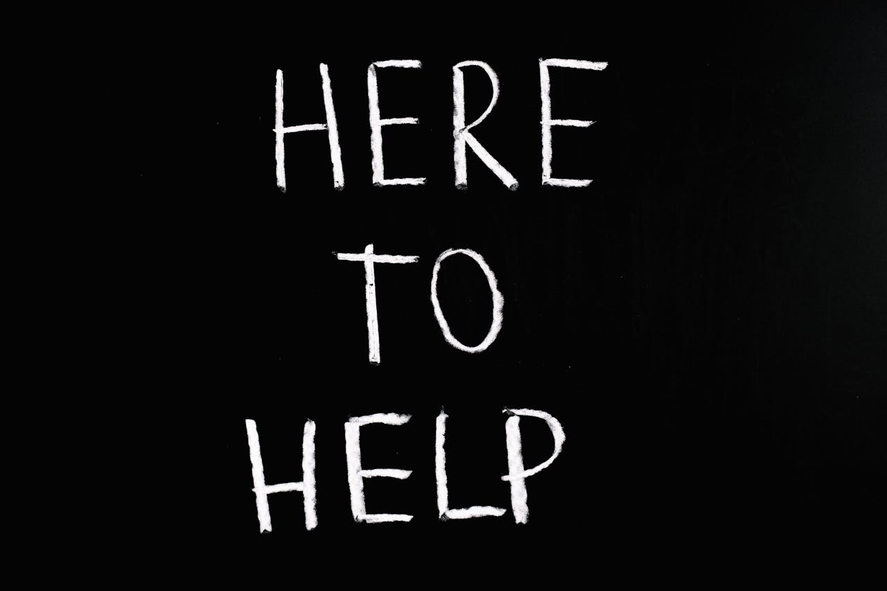 services-04 White text 'Here to Help' on a minimalist black chalkboard background, conveying encouragement and support.